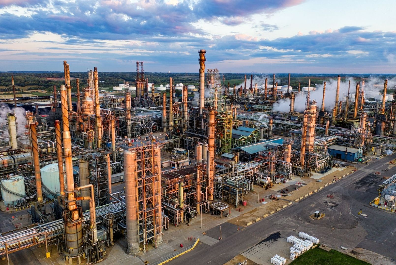 Aerial view of a sprawling industrial refinery with towers, pipes, and steam