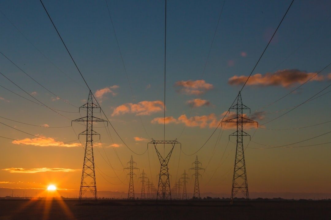 High-voltage transmission towers and power lines silhouetted at sunset