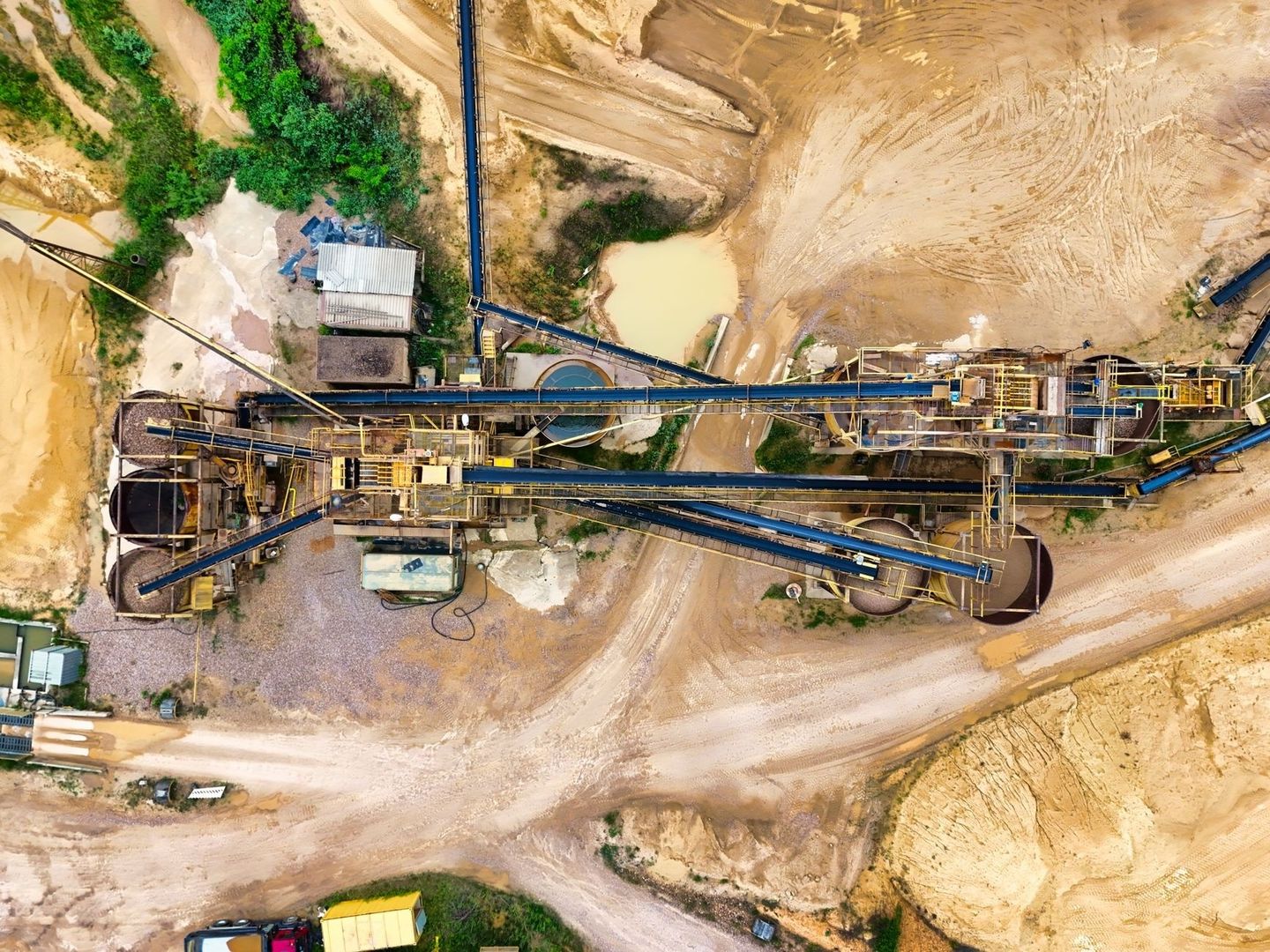 Aerial view of a mineral processing plant with conveyors and settling ponds